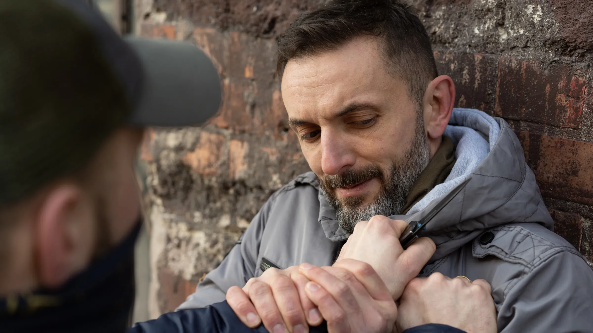 Késvédelmi gyakorlat közelről — két kéz a támadó pengét fogó kezét a testhez szorítja